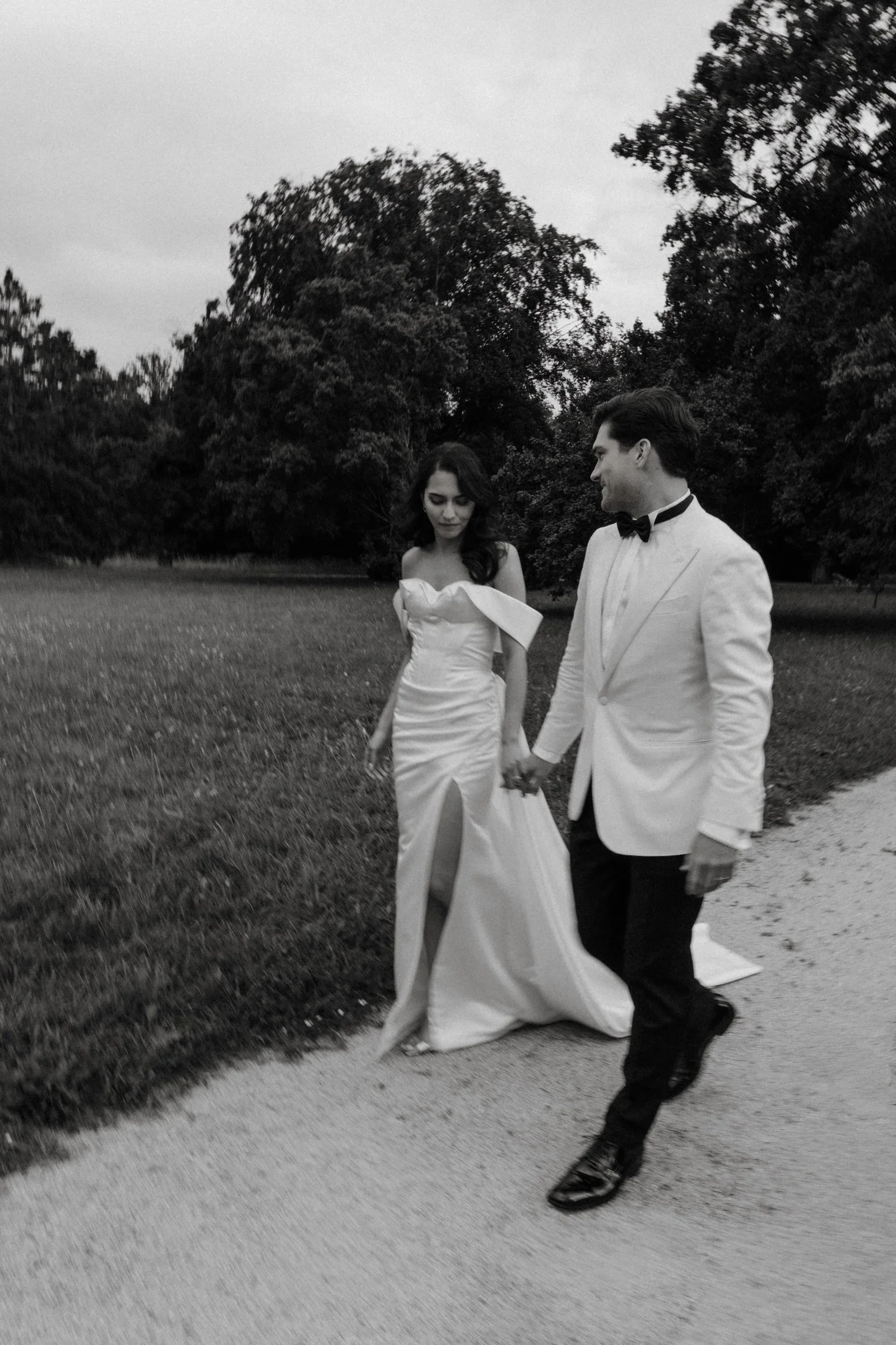 Couple walking on a gravel path next to the lawn, black and white
