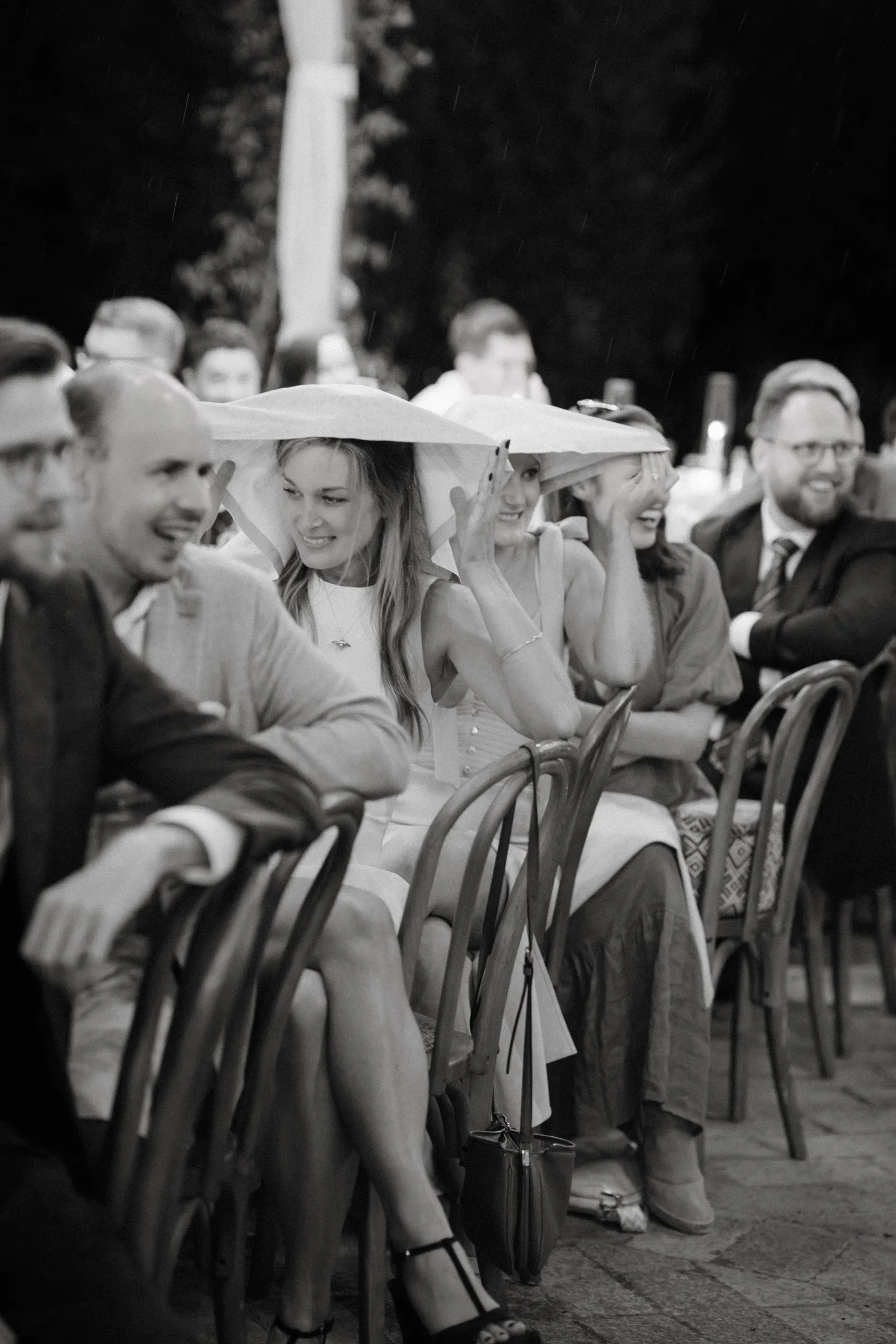 Black and white: guests watching the speeches, one leaning on another's shoulder