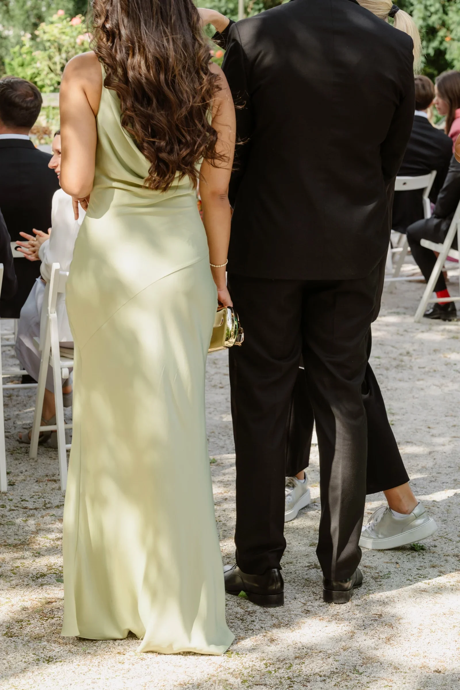 Woman in a pale green satin gown walking beside a man in a black suit