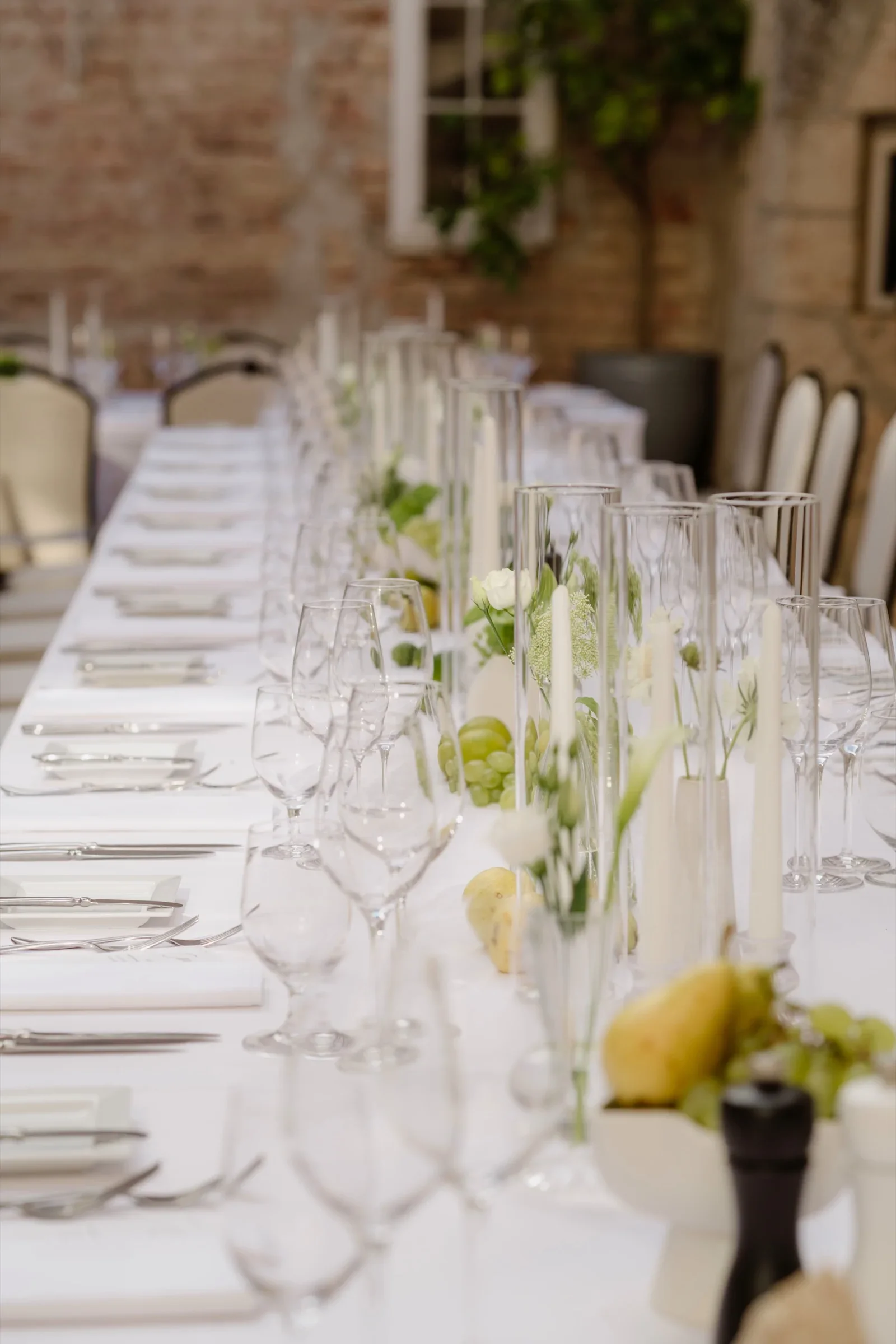 Close view of a long reception table with glasses, candles and lemons
