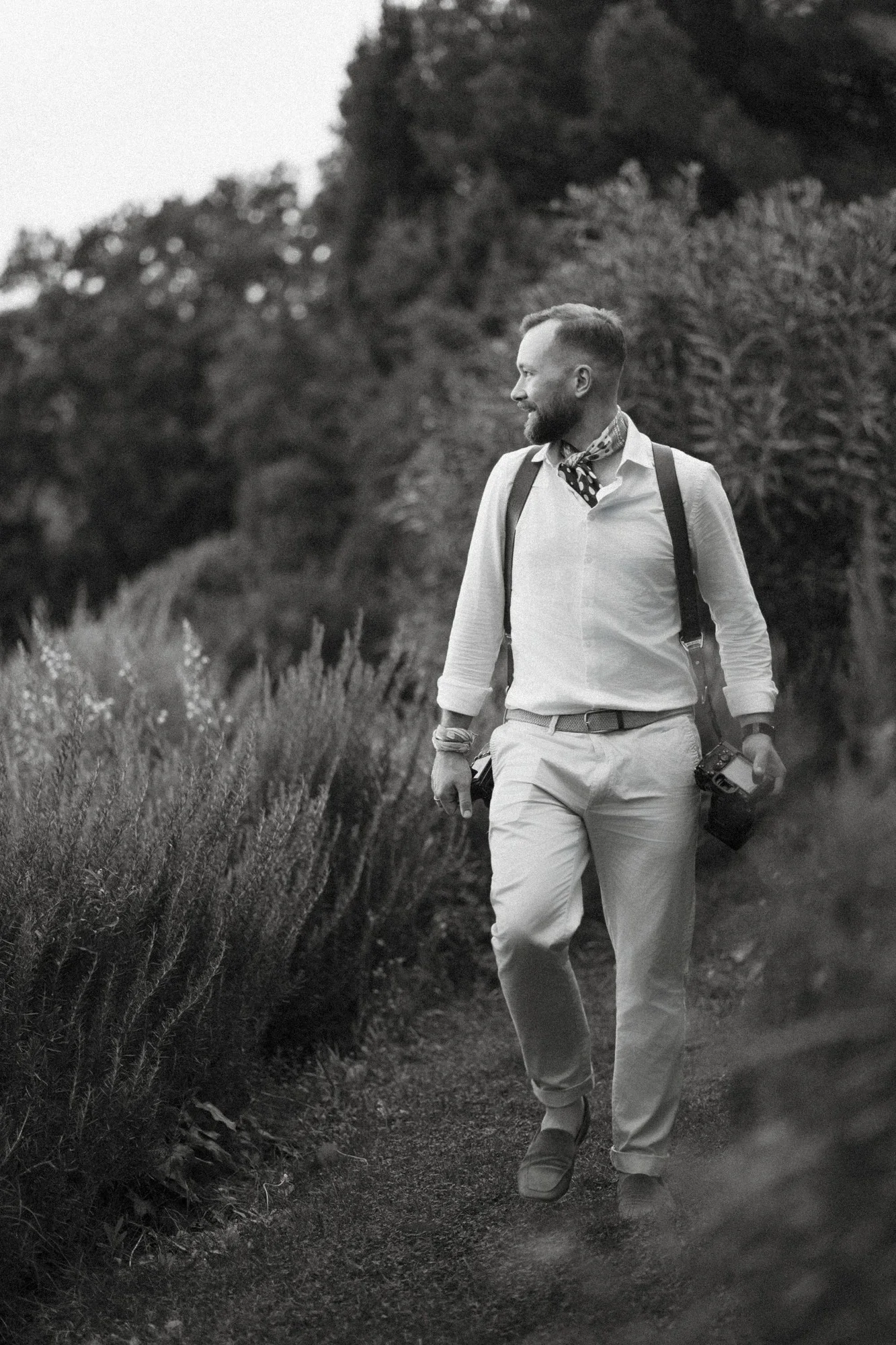Jakob Resch, Hochzeitsfotograf aus Wien, auf einem von Hecken gesäumten Gartenweg — Schwarzweißporträt