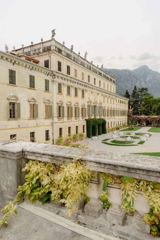 Neoclassical lakeside villa with formal gardens and mountains behind