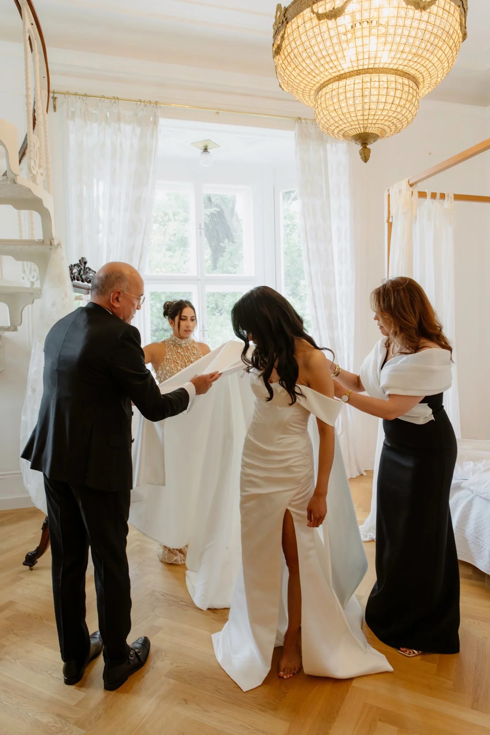 Father and bride in a wedding dress with the mother in a bright room with a chandelier