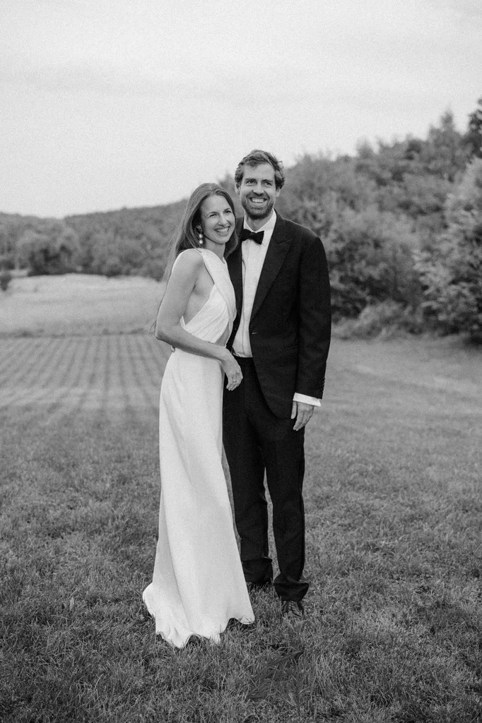 Couple standing arm in arm in an open meadow at dusk