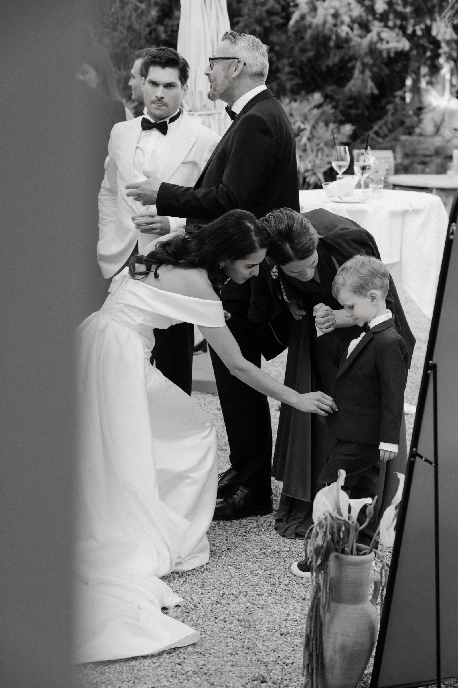 Black and white photo of guests bending over the bride's long dress train