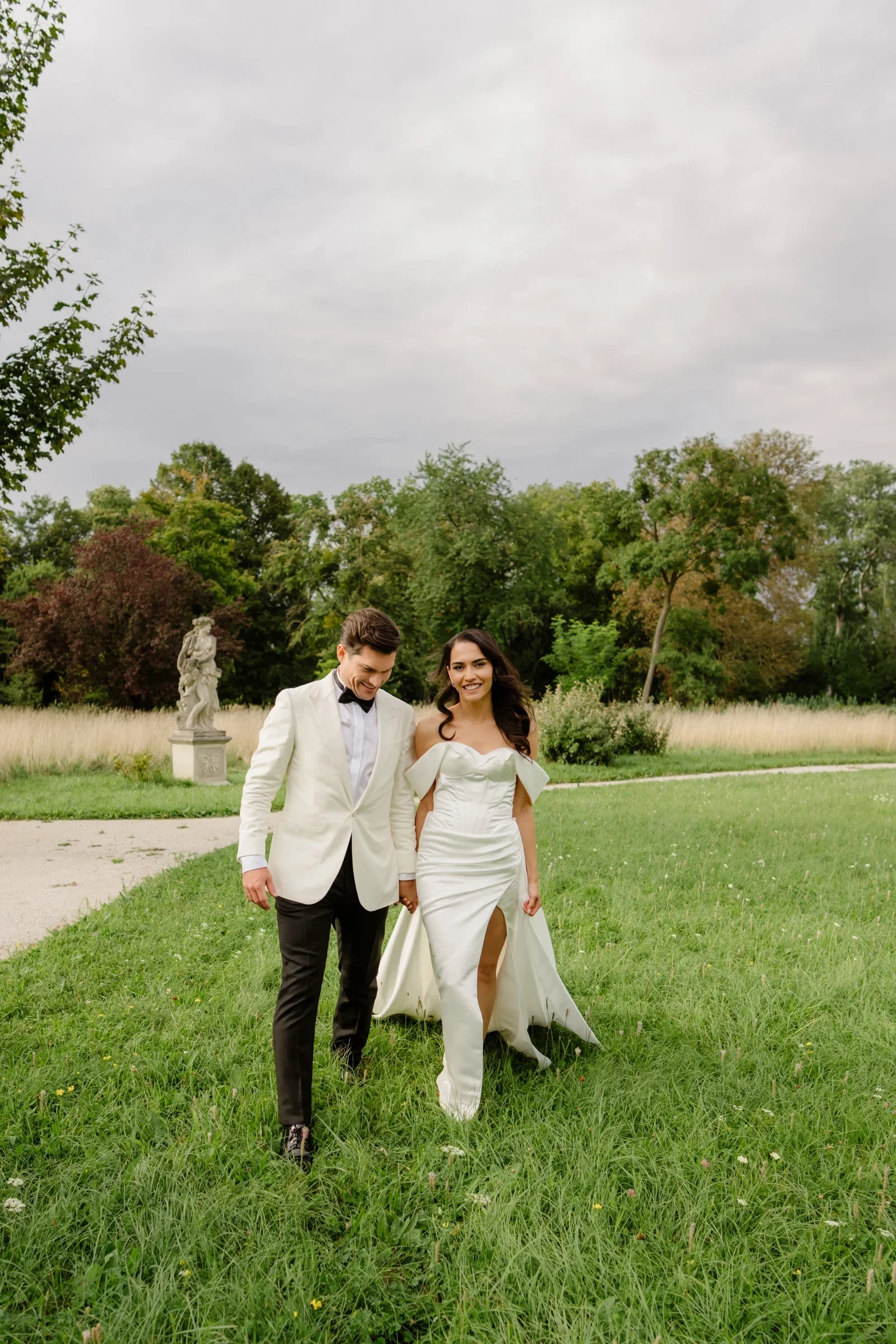 Couple walking hand in hand across a green lawn