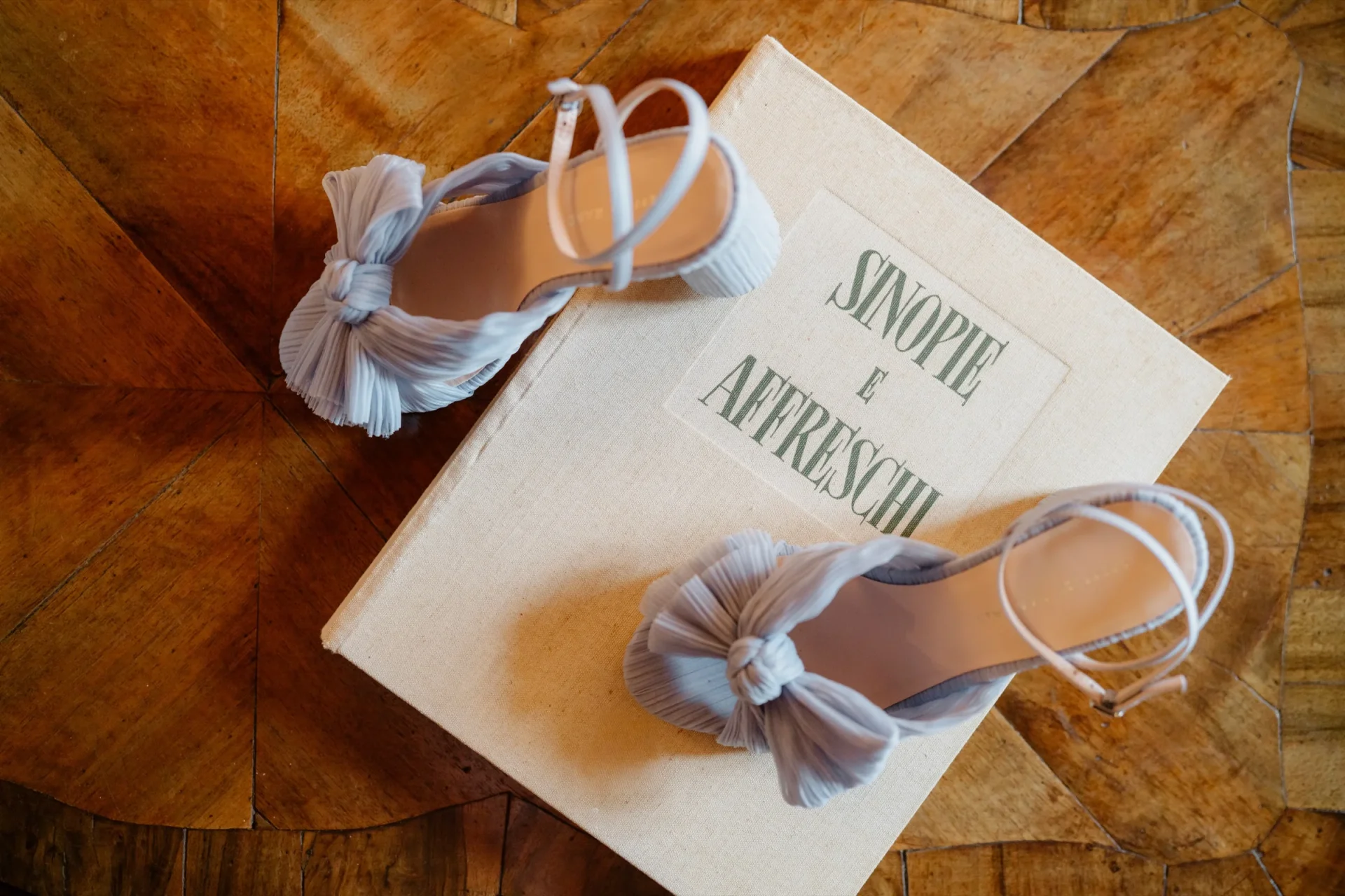 The blue wedding shoes set on a book about Sinopie and Italian frescoes