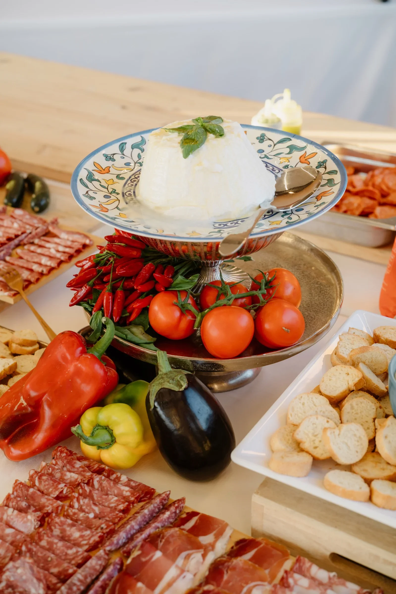 Long antipasti table with burrata, cured meats, peppers and tomatoes under the dinner tent