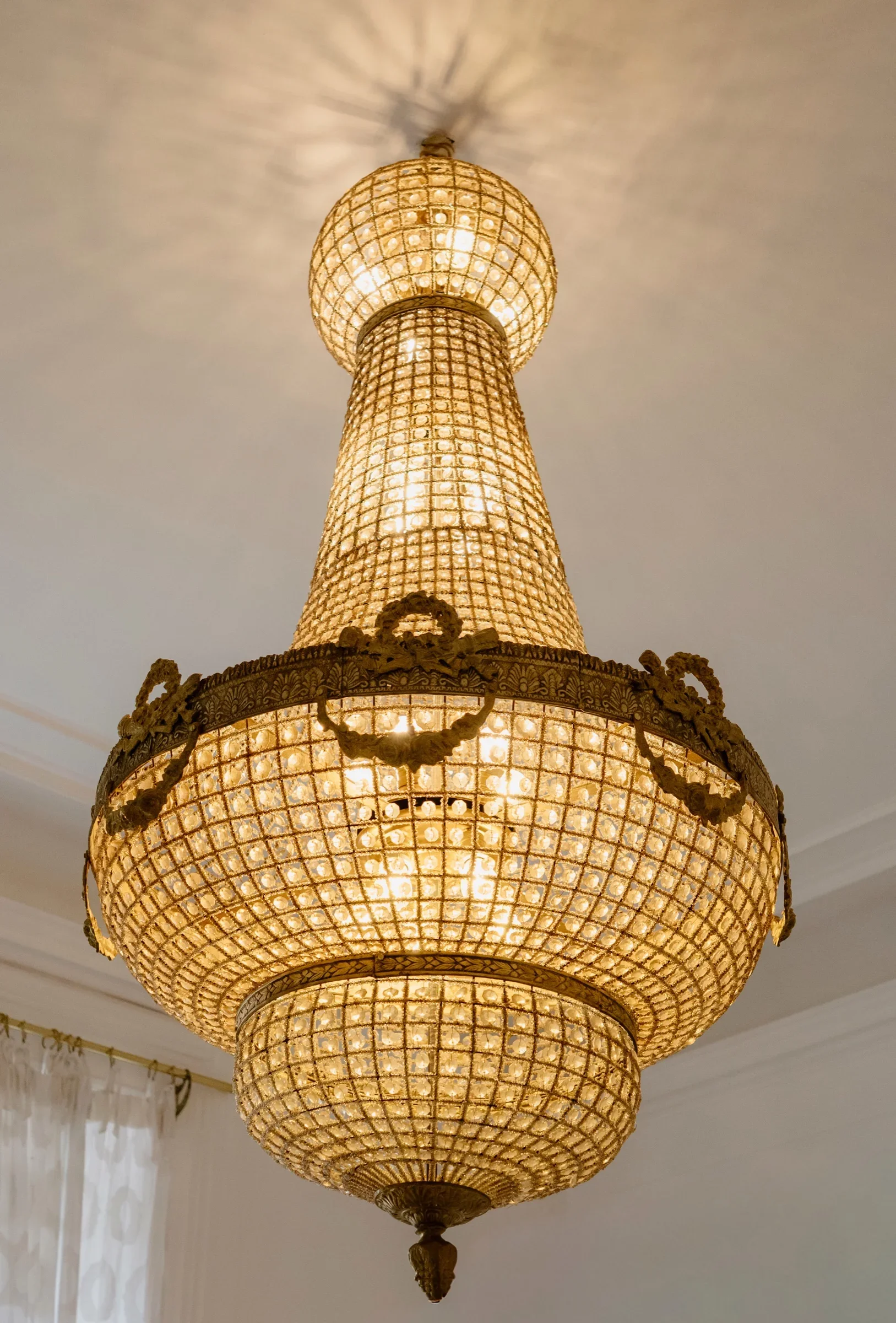 Ornate crystal chandelier glowing warmly in a bright room